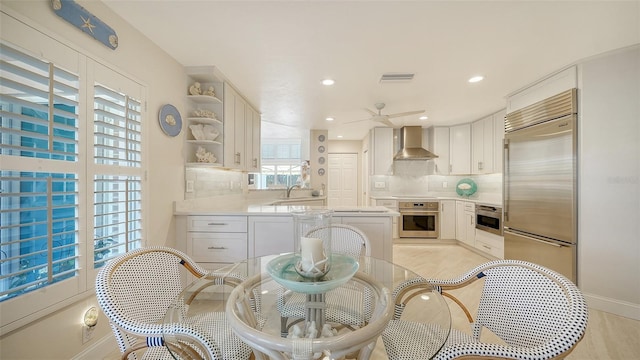 kitchen with visible vents, backsplash, wall chimney exhaust hood, and appliances with stainless steel finishes