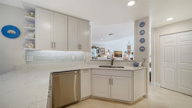 kitchen with light stone countertops, stainless steel dishwasher, decorative backsplash, open shelves, and a sink