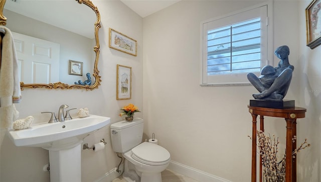 bathroom with baseboards, toilet, and a sink