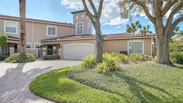 mediterranean / spanish-style house featuring central air condition unit, a front lawn, and a garage