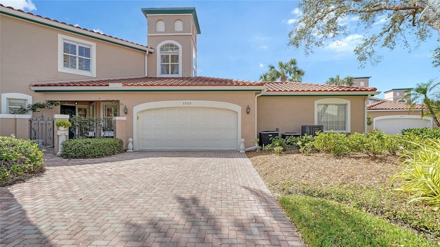 mediterranean / spanish-style home with central AC unit and a garage