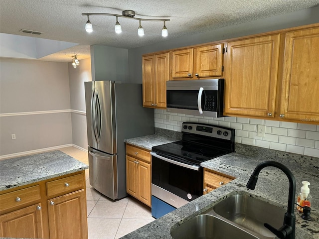 kitchen with appliances with stainless steel finishes, decorative backsplash, sink, and a textured ceiling