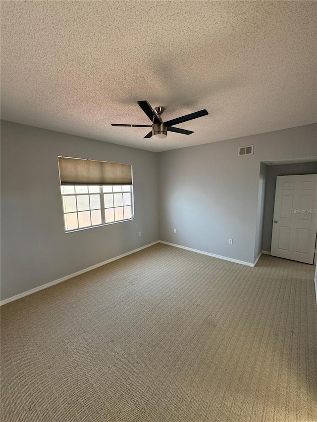 carpeted empty room featuring a textured ceiling and ceiling fan