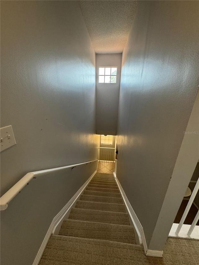 stairs with carpet and a textured ceiling