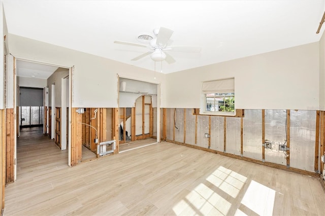 empty room featuring light wood-type flooring, ceiling fan, and wood walls