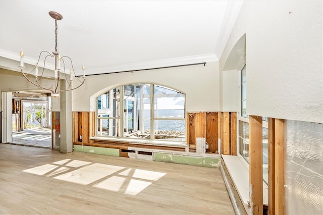 interior space featuring a water view, wood-type flooring, crown molding, and a chandelier