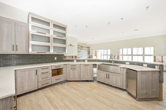 kitchen with light brown cabinets, light wood-type flooring, backsplash, and sink