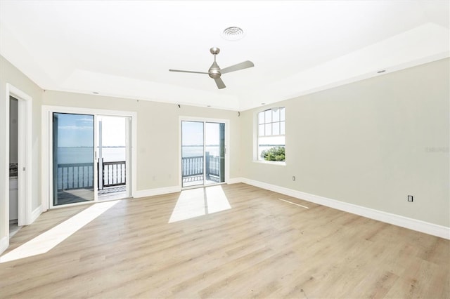 unfurnished room with light hardwood / wood-style floors, a raised ceiling, and ceiling fan