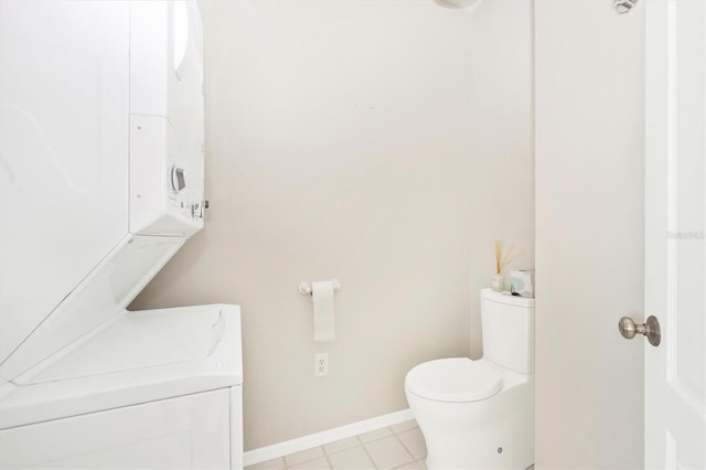 bathroom featuring stacked washer and dryer and toilet