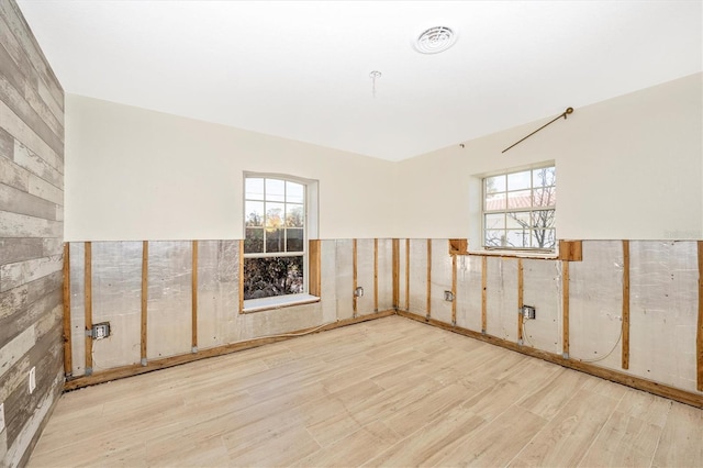 unfurnished room featuring light hardwood / wood-style floors and wooden walls