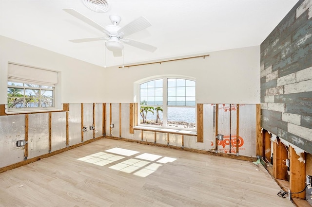 unfurnished room featuring ceiling fan, light hardwood / wood-style flooring, and a water view