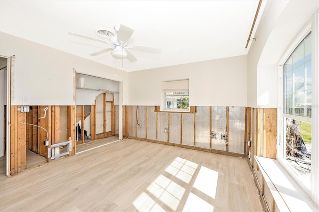 empty room featuring wooden walls, ceiling fan, and light hardwood / wood-style floors