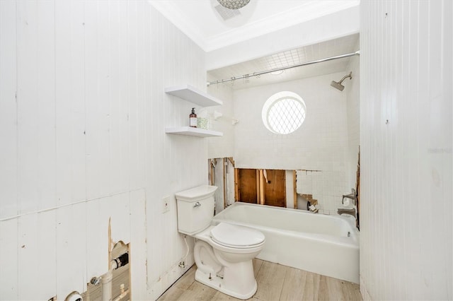 bathroom featuring ornamental molding, wooden walls, hardwood / wood-style flooring, toilet, and tiled shower / bath