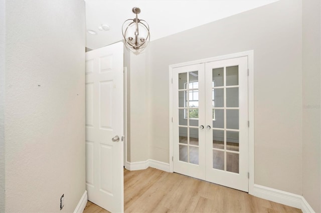 interior space featuring an inviting chandelier, french doors, and light hardwood / wood-style flooring