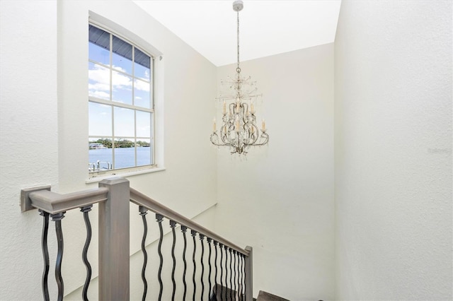 stairs with a water view and an inviting chandelier