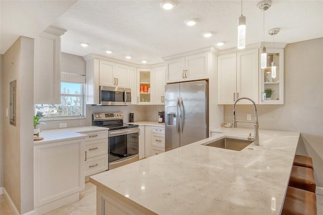 kitchen featuring hanging light fixtures, stainless steel appliances, kitchen peninsula, sink, and light stone counters