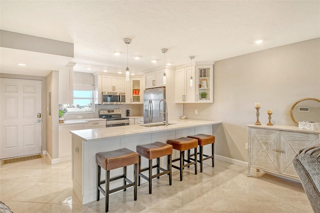 kitchen with hanging light fixtures, kitchen peninsula, a breakfast bar, white cabinetry, and appliances with stainless steel finishes