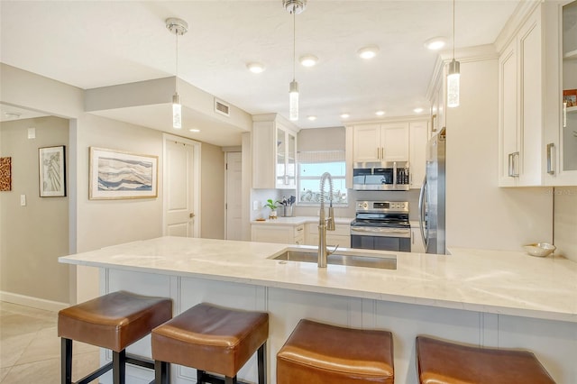 kitchen featuring appliances with stainless steel finishes, kitchen peninsula, decorative light fixtures, and a kitchen breakfast bar