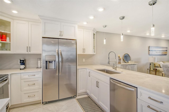 kitchen featuring hanging light fixtures, white cabinetry, light tile patterned flooring, sink, and stainless steel appliances