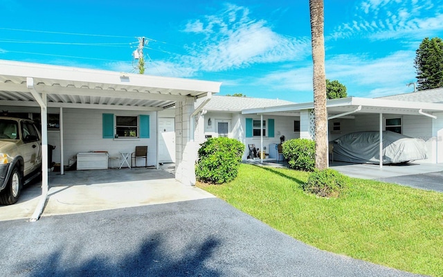 ranch-style house featuring a front lawn and a carport