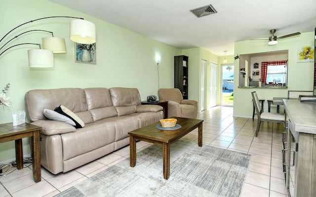 living room with a textured ceiling, ceiling fan, and light tile patterned floors