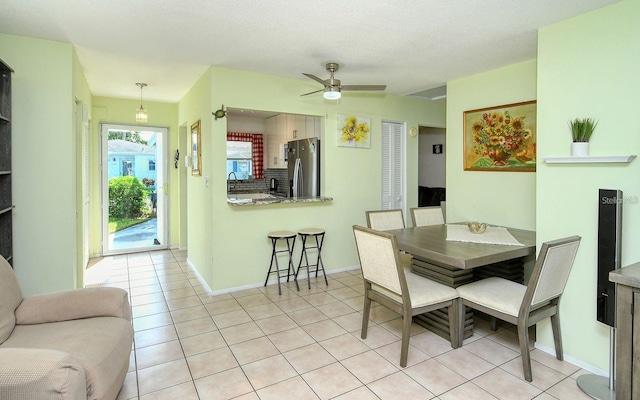 tiled dining area with ceiling fan and sink