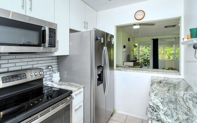 kitchen with decorative backsplash, appliances with stainless steel finishes, white cabinetry, and light tile patterned floors