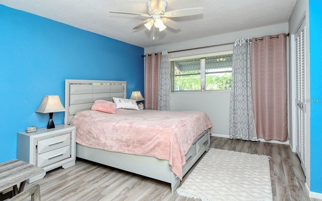 bedroom with light hardwood / wood-style floors, a textured ceiling, and ceiling fan