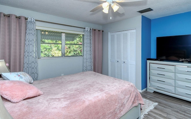 bedroom with hardwood / wood-style floors, a textured ceiling, and ceiling fan