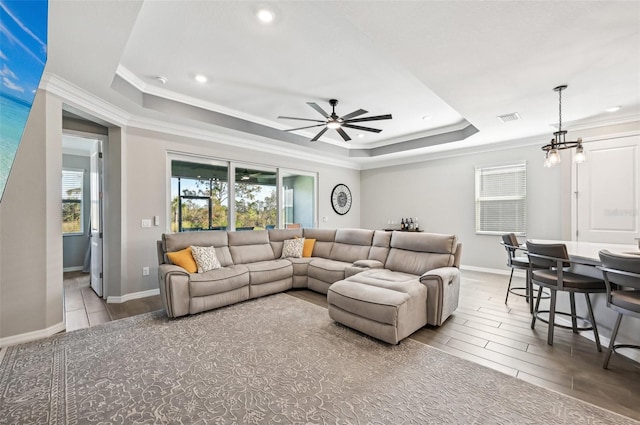 living room with crown molding, ceiling fan, and a raised ceiling