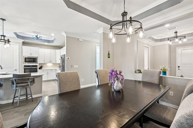 dining room featuring ornamental molding, sink, hardwood / wood-style flooring, and a raised ceiling