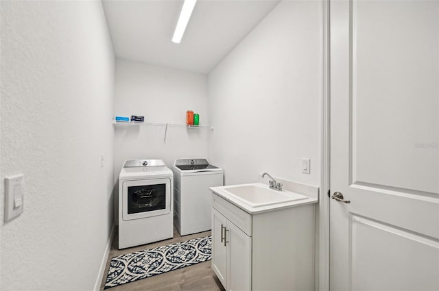 clothes washing area with sink, light hardwood / wood-style flooring, and independent washer and dryer