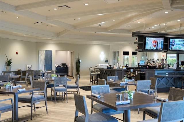 dining space featuring beam ceiling, crown molding, light hardwood / wood-style flooring, and indoor bar