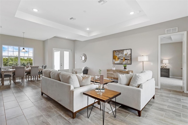 living room with french doors and a raised ceiling