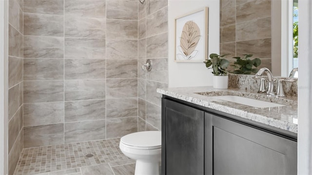 bathroom with vanity, toilet, a tile shower, and tile patterned flooring