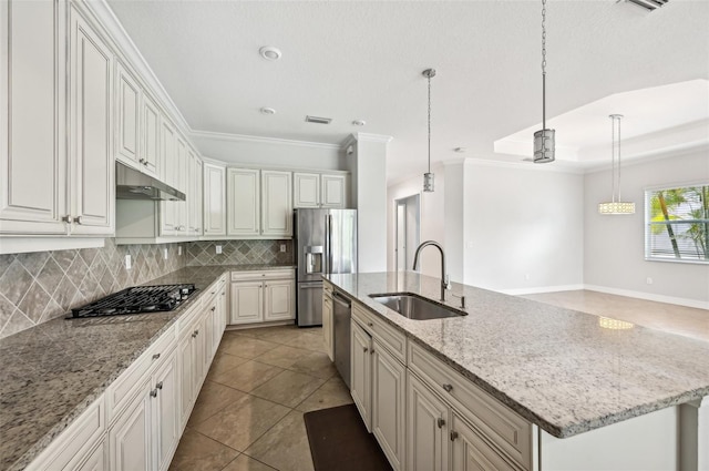 kitchen with a center island with sink, light stone counters, ornamental molding, stainless steel appliances, and sink