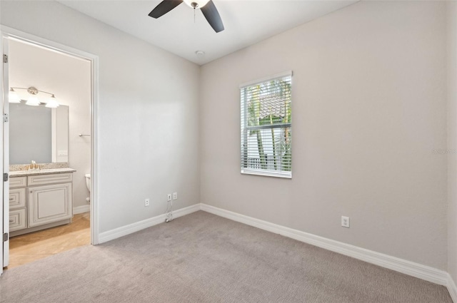 unfurnished bedroom with connected bathroom, light colored carpet, and ceiling fan