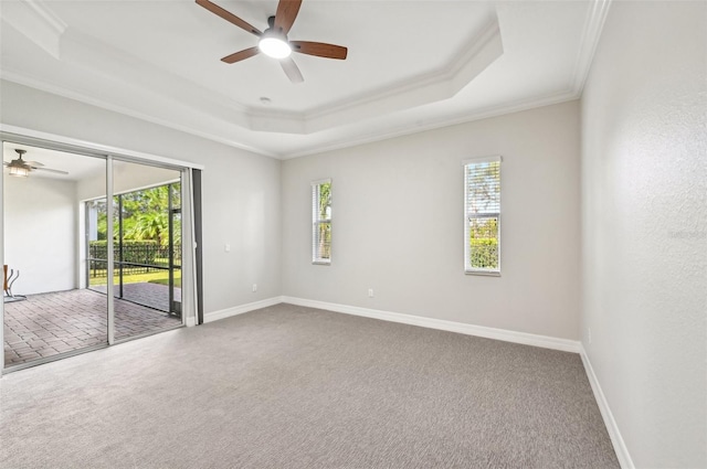 empty room with ceiling fan, a raised ceiling, ornamental molding, and carpet floors