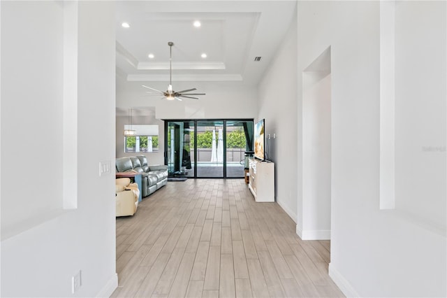 corridor featuring a tray ceiling and light wood-type flooring