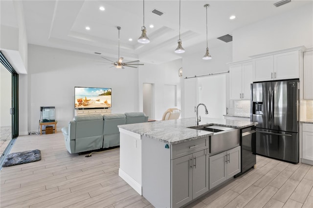 kitchen featuring appliances with stainless steel finishes, sink, a barn door, pendant lighting, and a kitchen island with sink