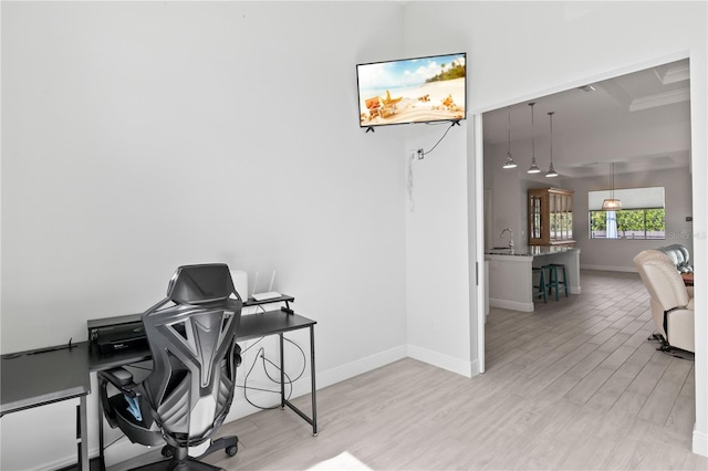 office space with beamed ceiling, sink, and light hardwood / wood-style floors