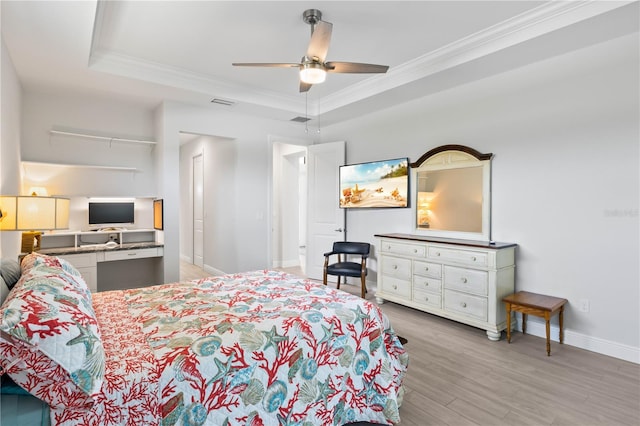 bedroom featuring a raised ceiling, crown molding, light wood-type flooring, and ceiling fan