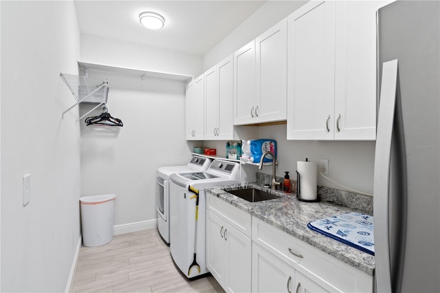 laundry area featuring light hardwood / wood-style floors, cabinets, sink, and washing machine and clothes dryer