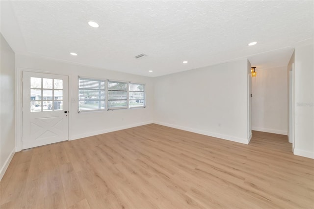 unfurnished room featuring light hardwood / wood-style floors and a textured ceiling