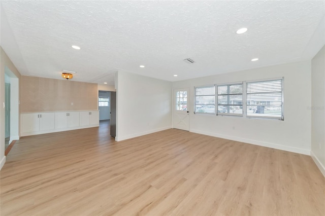 empty room with light hardwood / wood-style floors and a textured ceiling