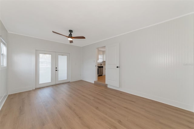 empty room with french doors, crown molding, light wood-type flooring, and ceiling fan