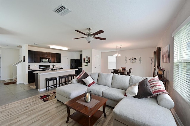 living room featuring sink, ceiling fan with notable chandelier, and light hardwood / wood-style flooring