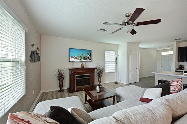 living room featuring a textured ceiling, hardwood / wood-style flooring, and ceiling fan