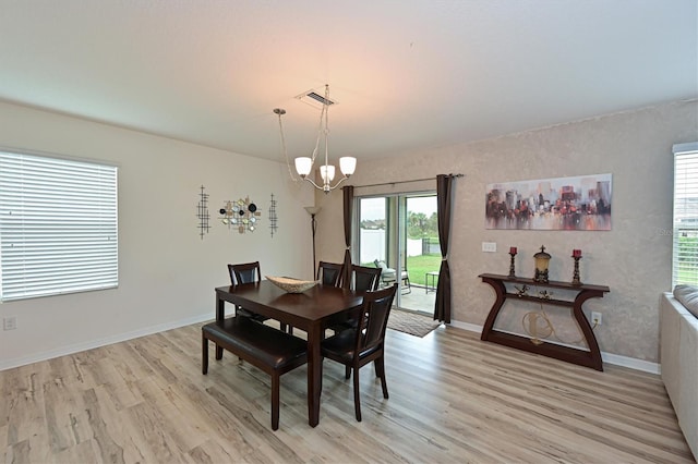 dining space with light wood-type flooring and an inviting chandelier