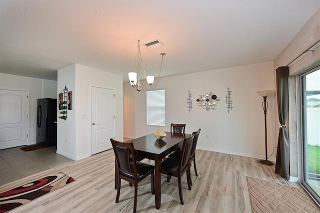 dining room with light wood-type flooring and a chandelier